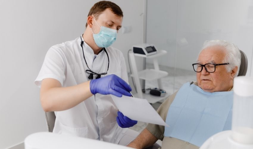 Diş hekimi, ileri yaştaki hastaya implant tedavi sürecini anlatıyor.